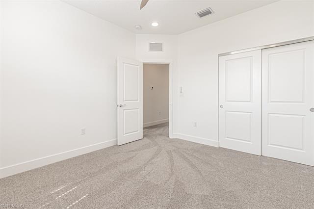 Unfurnished bedroom featuring baseboards, light colored carpet, and visible vents