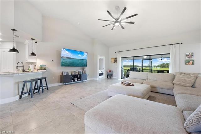Living area with light tile patterned floors, high vaulted ceiling, baseboards, visible vents, and ceiling fan