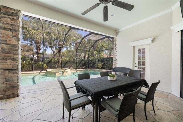View of patio featuring ceiling fan, outdoor dining space, a pool with connected hot tub, and a lanai